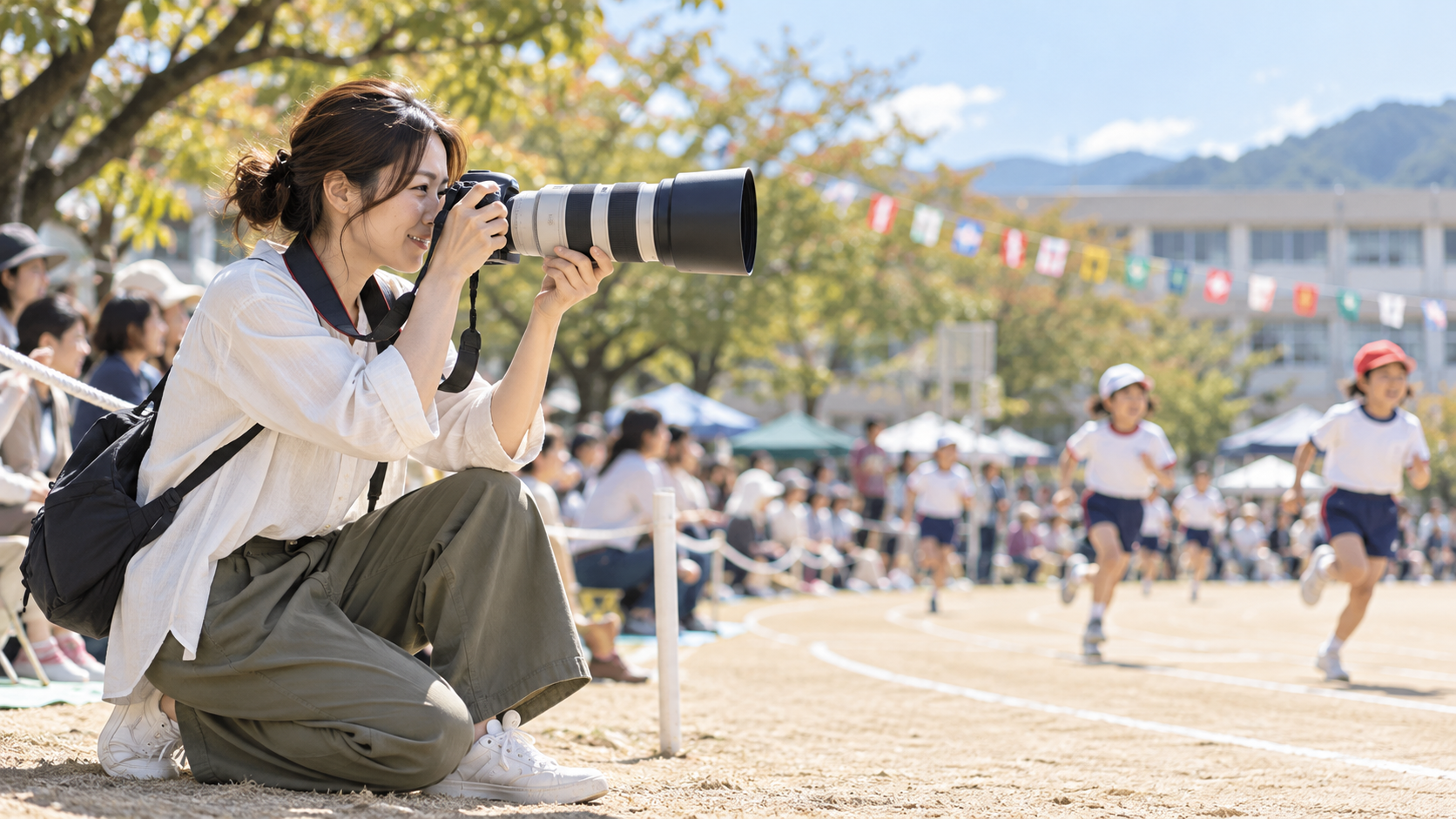 運動会で望遠レンズを装着したカメラを構え、走る子どもたちを撮影する女性。
